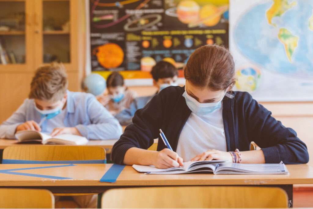 Ragazzi a scuola che studiano con la mascherina