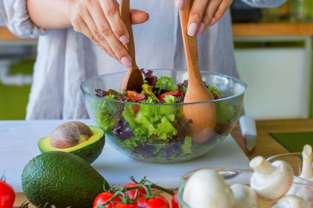 Dieta alimentare, donna che condisce un'insalata