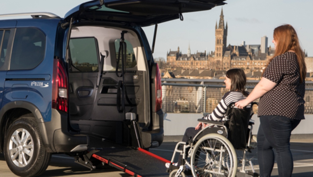 Ragazza in carrozzina sulla rampa di auto per persone con disabilità