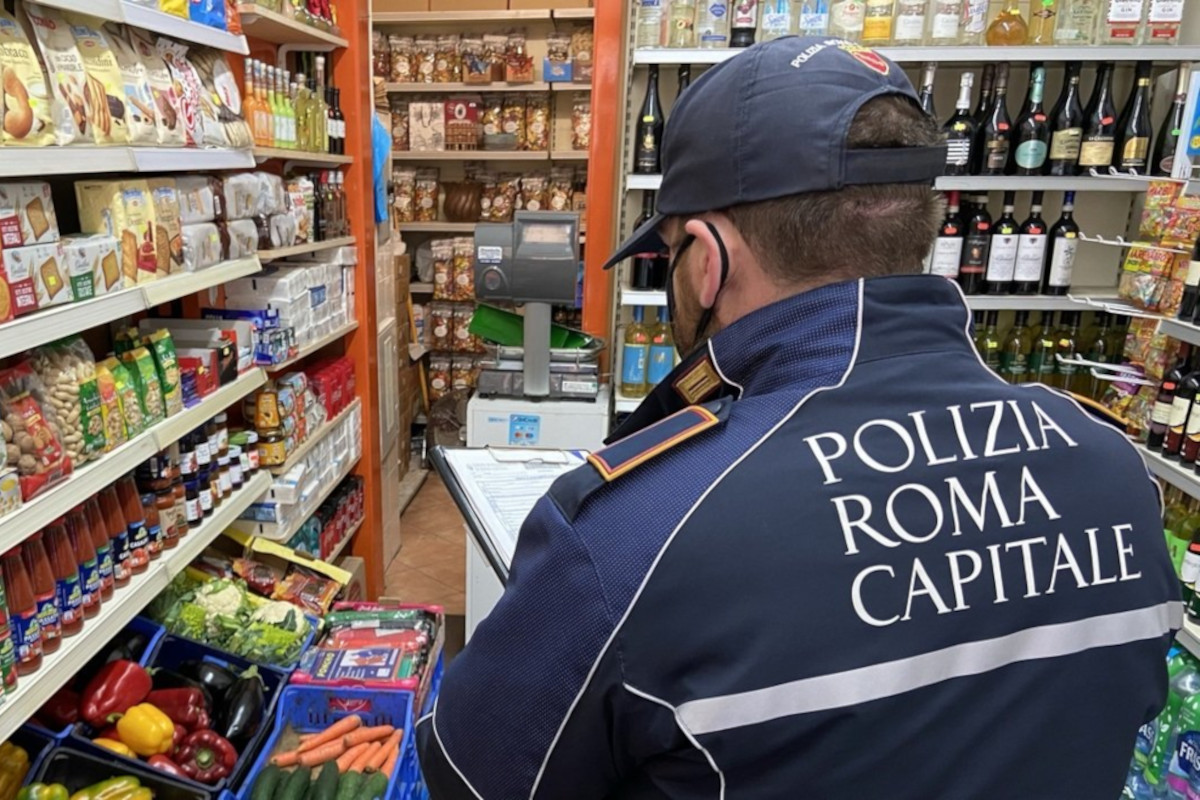 Poliziotto Roma capitale controlla interno di un minimarket
