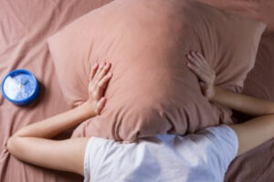 donna nel letto con cuscino sulla testa