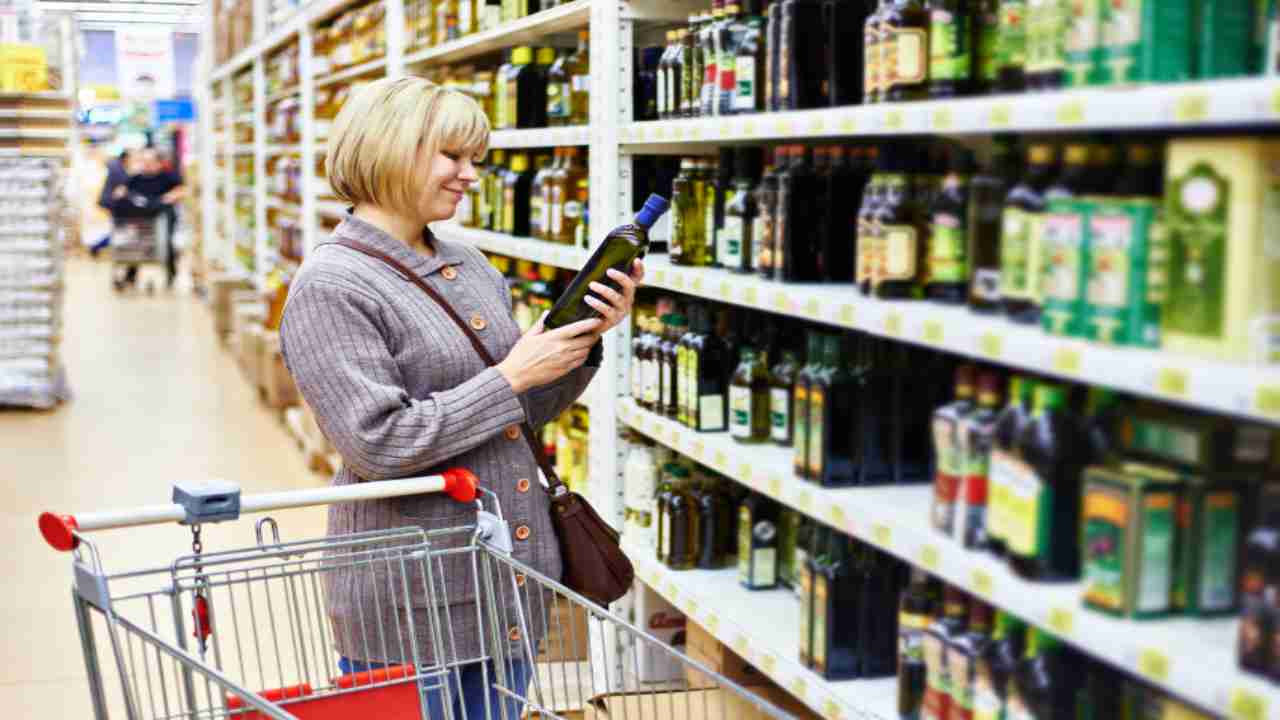 Donna legge l'etichetta di una bottiglia di olio al supermercato