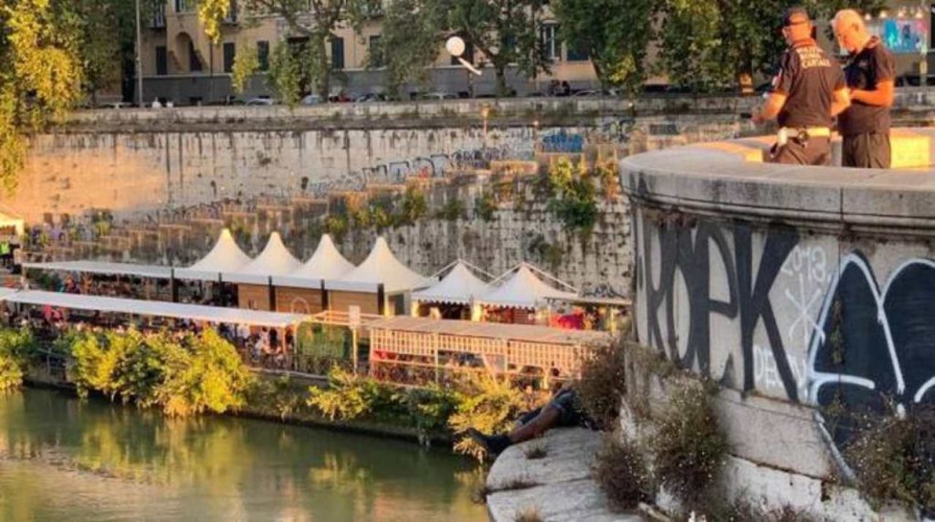 uomo disteso sul cornicione di un ponte a roma