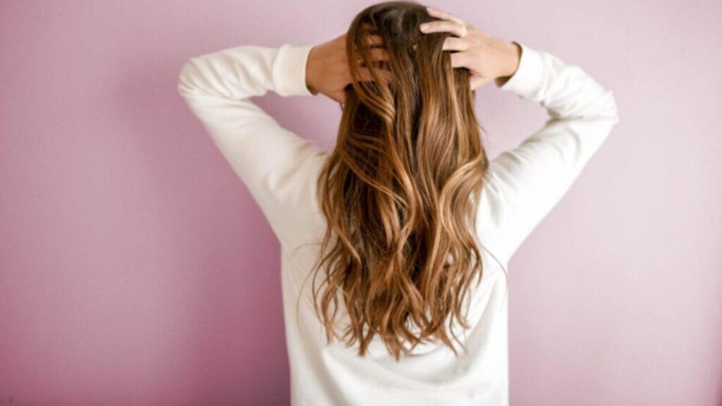 Donna di spalle accarezza i suoi lunghi capelli