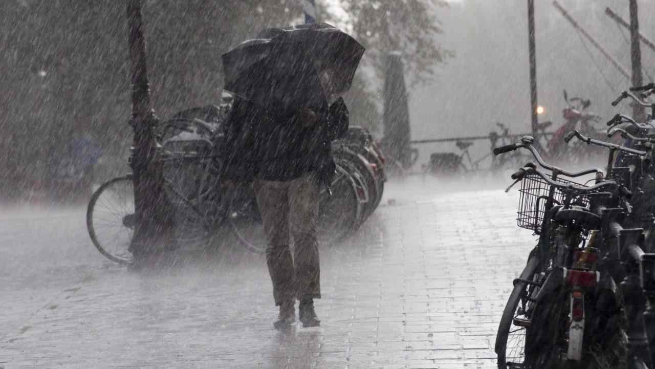 Una persona sotto l'ombrello e sotto la pioggia incessante