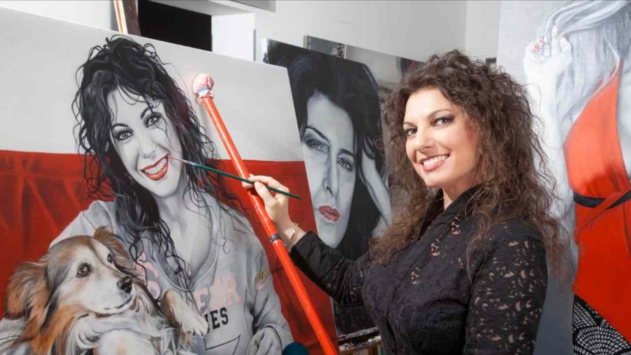 Cinzia Pellin mentre dipinge un quadro, sorridente