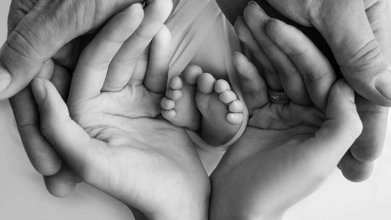 Piedi neonato tra le mani di un uomo e una donna, foto in bianco e nero