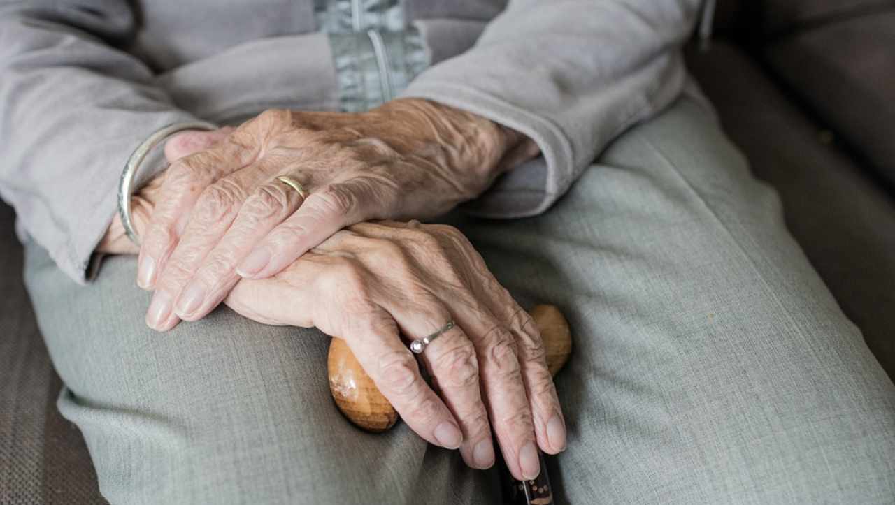 Mani di un'anziana con bastone