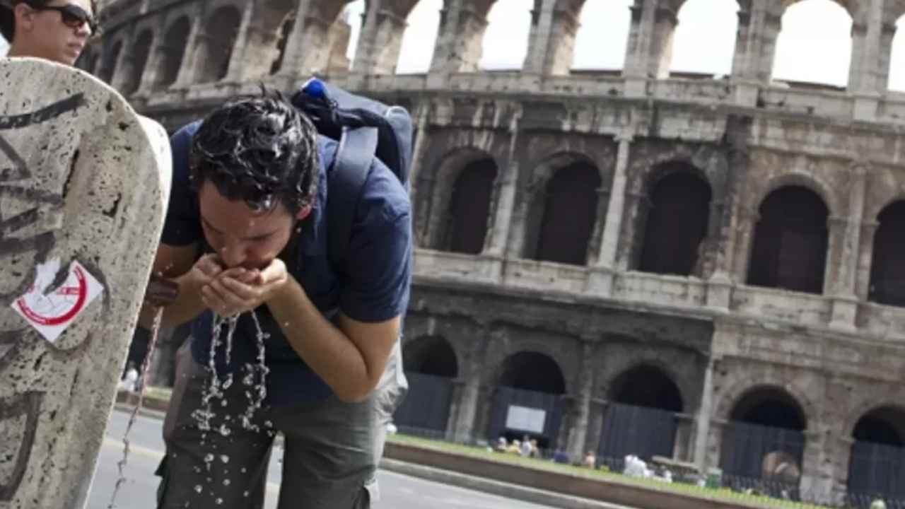 Un turista beve alla fontana per il caldo a Roma