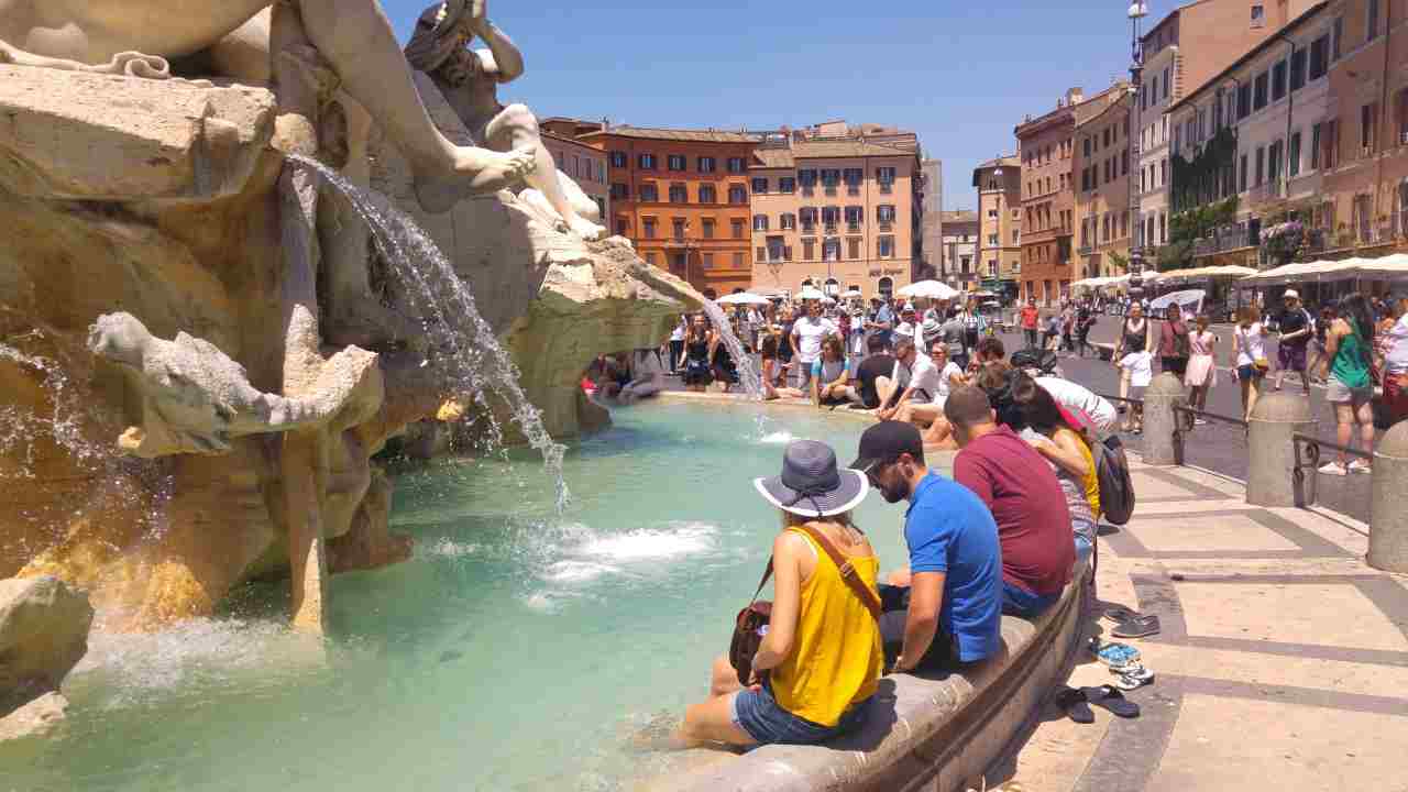 Fontana dei Quattro Fiumi a Piazza Navona di Roma, turisti immergono i piedi nella vasca