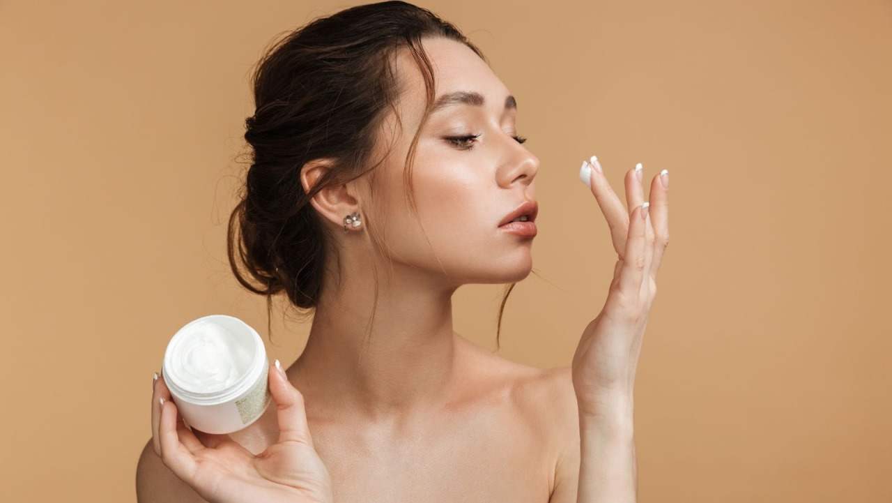 Giovane donna che si mette la crema antirughe