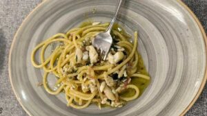 Spaghettone Gentile mantecato all’aglio nero fermentato in casa, con triglie e carciofi alla romana del ristorante "Romolo Al Porto" di Anzio
