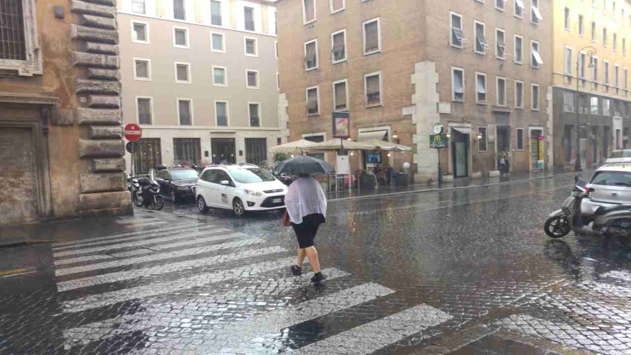 Pioggia a Roma, donna con ombrello attraversa la strada