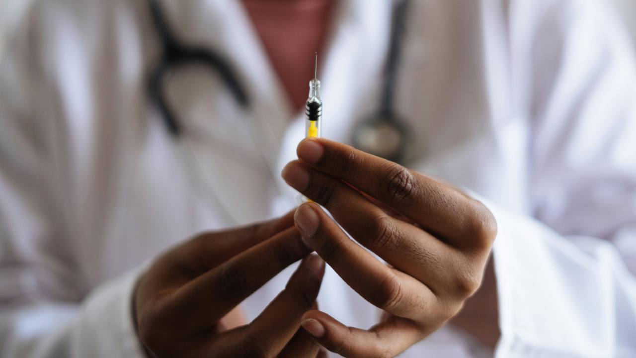 Vaccino, le dita delle mani di un medico stringono una piccola siringa per iniettare il vaccino