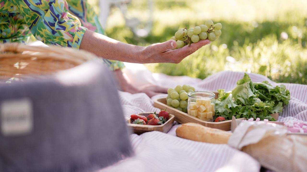 Picnic, mano femminile porge grappolo di uva, pexels shvets production